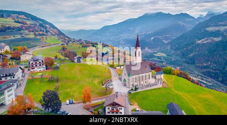 Düsterer Herbstblick von der fliegenden Drohne der Pfarrkirche Feldthurns. Abendliches Stadtbild des Dorfes Velturno, Provinz Bozen, Südtirol, Stockfoto