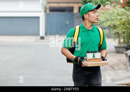 Fahrer in grüner Uniform bringt dem Kunden das Mittagessen Stockfoto