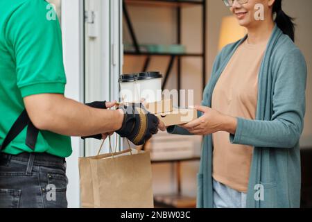 Glückliche Frau, die Pakete mit Essen vom örtlichen Coffeeshop erhält Stockfoto