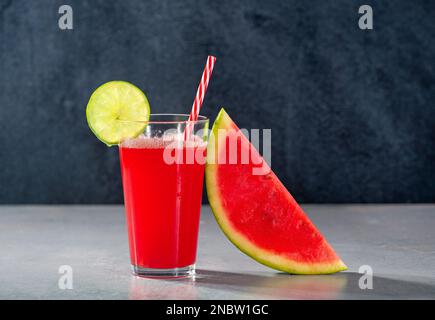 Frischer Wassermelonensaft mit einer Scheibe Limette und einer Scheibe Wassermelone gegen das Trinkglas Stockfoto