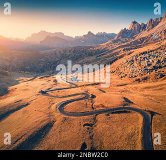 Blick von der fliegenden Drohne auf die gewundene Straße in den Dolomiten-Alpen. Großer Sonnenaufgang auf dem Giau Pass, Provinz Belluno in Italien, Europa. Fantastische Herbstszene von mir Stockfoto