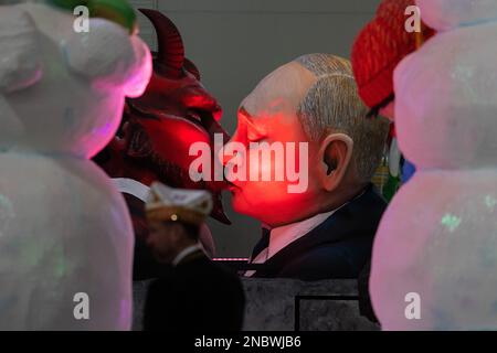 Köln, Deutschland. 14. Februar 2023. Ein Themenwagen, auf dem der russische Präsident Wladimir Putin den Teufel küsst, wird bei der Bestendigungszeremonie für die Parade am Kölner Rosenmontag in Koelnmesse enthüllt. Kredit: Rolf Vennenbernd/dpa/Alamy Live News Stockfoto