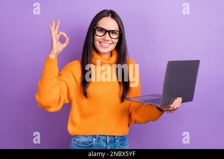 Foto des jungen Programmierers hübscher, charmanter Projekt-seo-Manager zeigt OKY-Schild mit Empfehlung des neuen asus-Laptops isoliert auf violettem Hintergrund Stockfoto