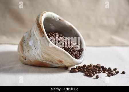 Verschüttete Kaffeebohnen aus Keramik auf Textil background.selective FOCUS Stockfoto