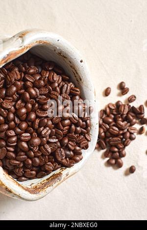Verschüttete Kaffeebohnen aus Keramik auf Textil background.selective FOCUS Stockfoto
