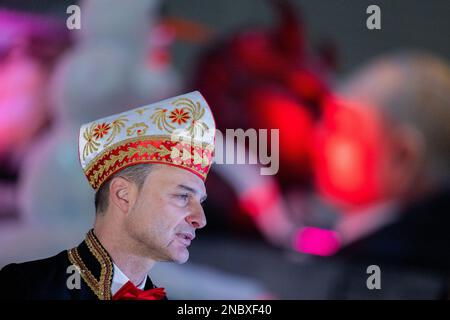 Köln, Deutschland. 14. Februar 2023. Holger Kirsch, Leiter der Kölner Rosenprozession am Montag, steht vor einem Themenwagen, auf dem der russische Präsident Wladimir Putin bei der Bestendigungszeremonie für die Kölner Rosenprozession am Montag in Koelnmesse den Teufel küsst. Kredit: Rolf Vennenbernd/dpa/Alamy Live News Stockfoto