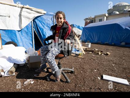 Kirikhan, Türkei. 14. Februar 2023. Die achtjährige Rabia sitzt vor einem provisorischen Zelt, wo sie sich jetzt mit ihrer Familie beherbergt. Mehr als eine Woche nach den verheerenden Erdbeben in der Türkei und in Syrien besteht kaum Hoffnung, noch mehr Überlebende unter den Trümmern zu finden. Kredit: Boris Roessler/dpa/Alamy Live News Stockfoto