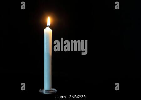 Nahaufnahme eines einzelnen Kerzenlichts und einer Flamme auf schwarzem Hintergrund Kopierbereich, Stockfoto