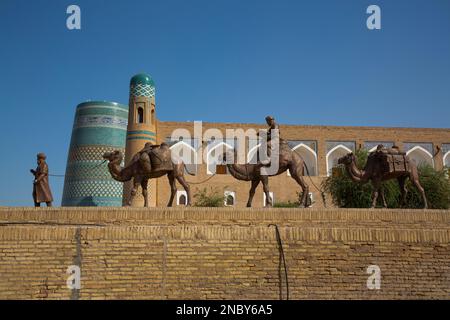 Skulptur des Kamelzugs, Kalta Minaret (Hintergrund), Ichon Qala, Khiva, Usbekistan Stockfoto