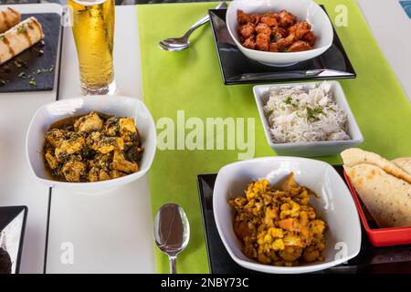 Eine Nahaufnahme verschiedener indischer Gerichte auf einem weißen Tisch mit grüner Tischdecke Stockfoto