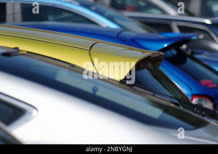 Autos füllen einen Parkplatz. Die Autos sind Gold, Blau und Silber. Stockfoto