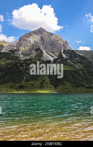 Vertikale Landschaft des wunderschönen grünen klaren Sees in Österreich. Tappenkarsee mit Hill und Rocky Peak während des Sommertags in Kleinarl. Stockfoto