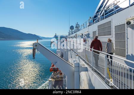 Touristen, die an Deck eines Kreuzfahrtschiffes entlang der Inside Passage zwischen Prince Rupert und Port Hardy, British Columbia, Kanada, spazieren. Stockfoto