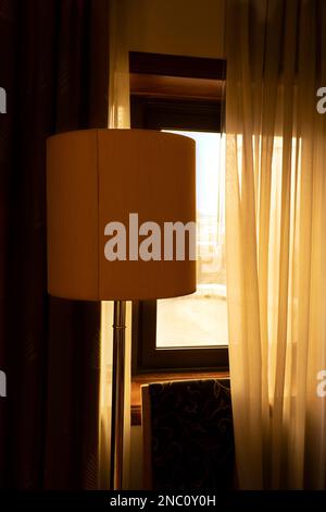 Morgensonne, die durch halb offene Vorhänge ins Zimmer kam Stockfoto