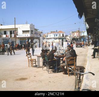 1960er, historisch, kretische Männer sitzen draußen an einem Tisch in der Straße Mires, Kreta, Griechenland. Stockfoto