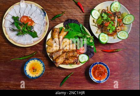 Traditionelle gebratene vietnamesische Frühlingsrollen mit Schweinefleisch, Reispapier mit Saucen, Fleischscheiben und Rindereintopf Stockfoto