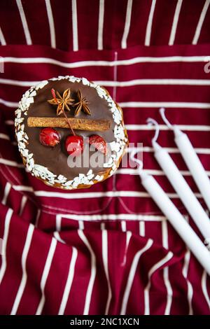 Ein traditioneller paska mit weißer und dunkler Schweizer Schokolade und Kirschen, Zimt und Sternanis steht auf einer Kirschschschürze. Osterholid Stockfoto