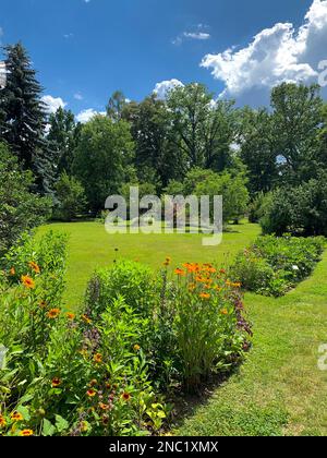 Hüttengarten mit bunten Blumen und grünem Rasen Stockfoto