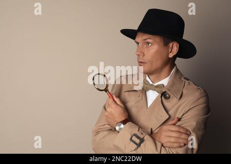 Männlicher Detective mit Lupe auf beigem Hintergrund. Platz für Text Stockfoto