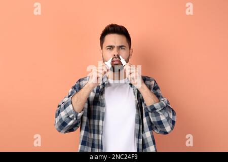 Mann mit Nasensprays auf pfirsichfarbenem Hintergrund Stockfoto