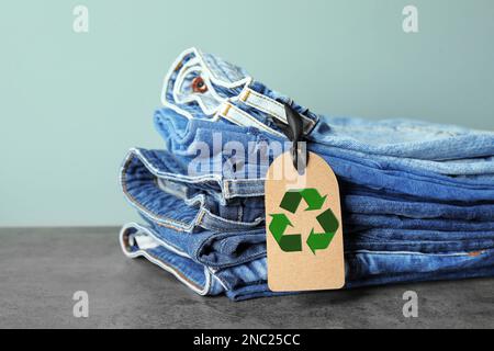 Ein Stapel Jeans mit Recycling-Etikett auf dem grauen Tisch Stockfoto