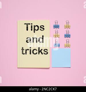 Notizbuch mit Text Tipps und Tricks auf pinkfarbenem Hintergrund, flach liegend Stockfoto