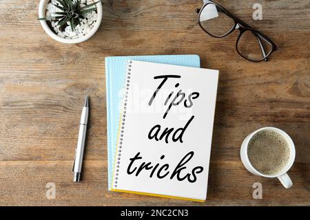 Notizbuch mit Text Tipps und Tricks auf Holztisch, flach liegend Stockfoto