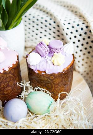 Farbenfrohe Ostereier liegen zusammen mit Ostergebäck mit bunter Schokolade auf einem Holztisch Stockfoto