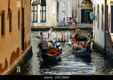 Gondeln mit Touristen auf dem Kanal Rio del Fontego dei Tedeschi mit Palazzo dei Camerlenghi mit Blick auf den Canale Grande im Hintergrund, Venedig, Italien Stockfoto