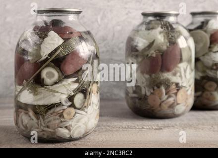 Verschiedene Gemüsesorten werden in Glasgefäßen konserviert: Gurken, Tomaten, Kohl, Zwiebeln, Karotten, Zucchini. Vorderansicht, Nahaufnahme. Stockfoto