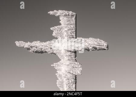 Schwarzweißfoto eines Winterkreuzes, bedeckt mit Schnee, das Werk des Windes in den Karpaten Stockfoto