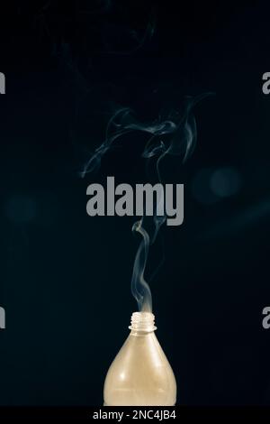 Beweglicher Rauch, der aus einer Plastikflasche austritt. Isoliert auf schwarzem Hintergrund. Stockfoto