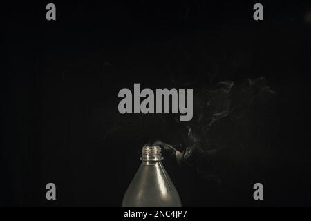 Rauch aus einer Plastikflasche vor schwarzem Hintergrund. Konstruktionselement. Aromatherapie. Stockfoto