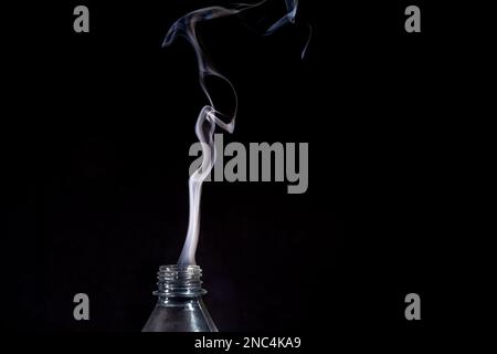 Eine transparente, isolierte Kunststoffflasche, aus der Rauch austritt. Konstruktionselement. Stockfoto