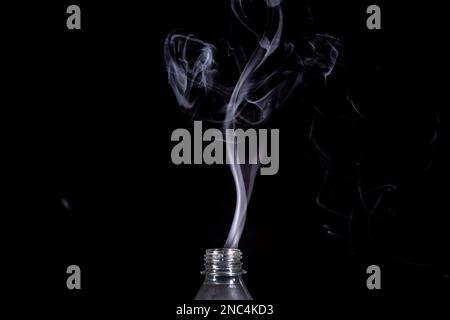 Eine transparente, isolierte Kunststoffflasche, aus der Rauch austritt. Konstruktionselement. Stockfoto