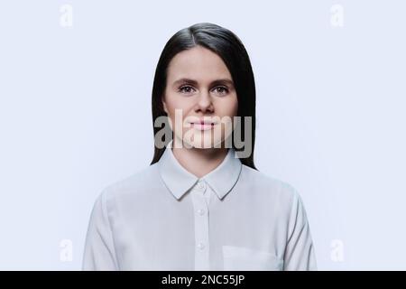Porträt einer jungen Frau, die auf weißem Hintergrund in die Kamera schaut Stockfoto