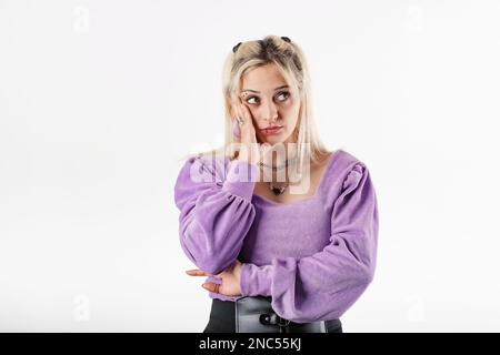 Eine junge weiße Frau mit Bluse, die isoliert auf weißem Hintergrund steht, neigt sich den Kopf auf die Handfläche und sieht den leeren Kopierraum pessimistisch an. Nein Stockfoto