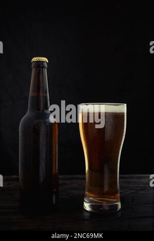 Eine Flasche und ein Glas Bier auf dunklem Hintergrund. Stockfoto