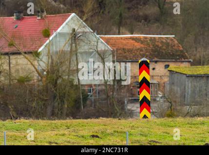 30. Januar 2023, Brandenburg, Schwedt/Oder: 30.01.2023, Schwedt/Oder. Ein deutscher schwarz-rot-goldener Grenzposten steht in der Nähe von Schwedt an der deutsch-polnischen Grenze der oder. Dahinter sind Gebäude auf der polnischen Seite zu sehen. (Foto mit starkem Teleobjektiv). Foto: Wolfram Steinberg/dpa Foto: Wolfram Steinberg/dpa Stockfoto