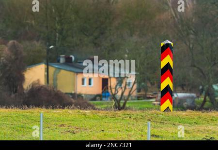 30. Januar 2023, Brandenburg, Schwedt/Oder: 30.01.2023, Schwedt/Oder. Ein deutscher schwarz-rot-goldener Grenzposten steht in der Nähe von Schwedt an der deutsch-polnischen Grenze der oder. Dahinter sind Gebäude auf der polnischen Seite zu sehen. (Foto mit starkem Teleobjektiv). Foto: Wolfram Steinberg/dpa Foto: Wolfram Steinberg/dpa Stockfoto