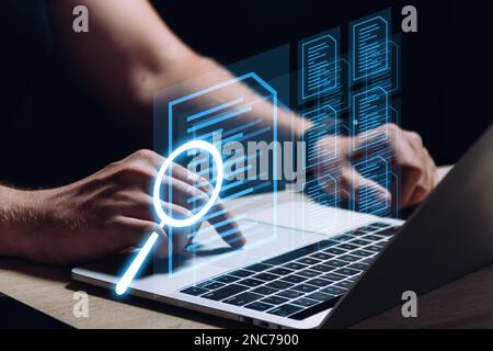 Eine Person arbeitet an einem Laptop und prüft Dokumente. Geschäftsführung. Stockfoto