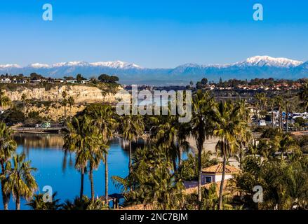 Blick auf die obere Bucht von Newport Beach und die schneebedeckten San Gabriel Berge an einem sonnigen Wintertag Stockfoto