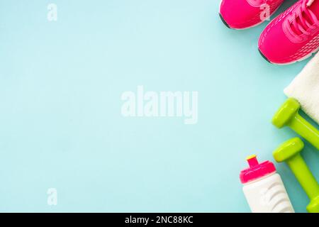 Kurzhanteln, Turnschuhe, Maßband, Wasserflasche und Notizblock auf blau. Stockfoto