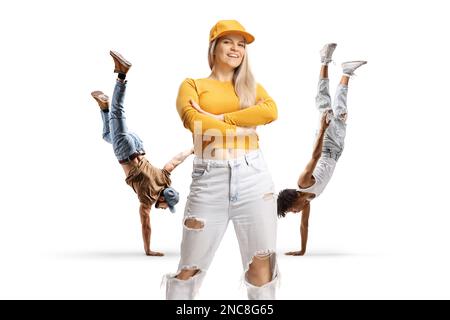 Männliche Tänzer, die einen Handstand aufführen, und eine junge Frau, die isoliert auf weißem Hintergrund davor steht Stockfoto