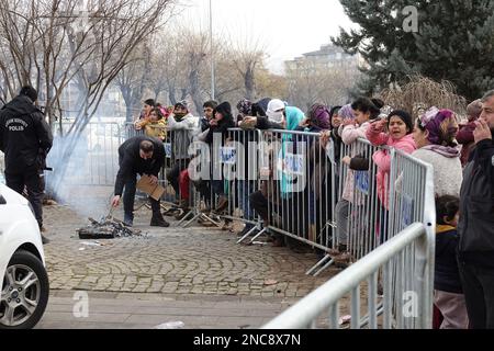 Diyarbakir, Türkei. 8. Februar 2023. Frauen und Kinder, die gezwungen sind, in Zeltstädten zu leben, warten auf die Verteilung von Nahrungsmittelhilfe, während einige Beamte ein Feuer für Wärme machen. 7 Gebäude in der Stadt wurden vollständig zerstört. Die Rettungsarbeiten in der Stadt wurden 9 Tage nach dem Erdbeben abgeschlossen. Die Zahl der Todesopfer erreichte 344. Es gibt fast 1000 Verletzte. In Diyarbakir gibt es insgesamt 307 Gebäude, von denen 26 zerstört werden, 25 sofort abgerissen werden müssen und 261 schwer beschädigt sind. Etwa 250.000 Menschen können ihr Zuhause nicht betreten. Sie leben entweder in Zeltstädten oder in sicheren Unterkünften Stockfoto