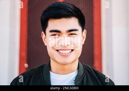 Nahaufnahme Porträt eines lustigen Asiaten, der draußen auf die Kamera schaut und lächelt. Hochwertiges Foto Stockfoto