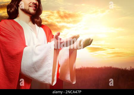 Jesus Christus streckte seine Hände aus und betete bei Sonnenuntergang Stockfoto