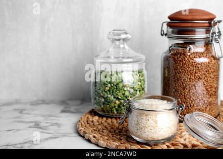Glasgefäße mit verschiedenen Grobgrießsorten auf einem weißen Marmortisch. Platz für Text Stockfoto