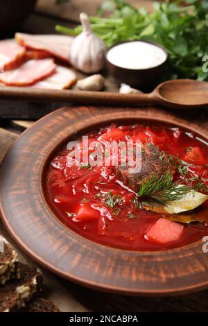 Stilvolle braune Tonplatte mit ukrainischem Borsch, serviert auf einem Holztisch, Nahaufnahme Stockfoto