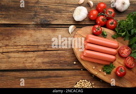 Frische rohe vegetarische Würste, Sojabohnen und Gemüse auf Holztisch, flach liegend. Platz für Text Stockfoto